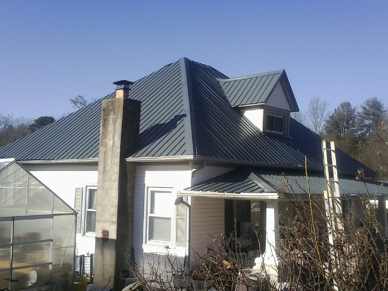 Dark blue standing seam metal roof on a white farmhouse with dormer — Slate & Tile Roof Repair by Roofing Brothers in Breckenridge